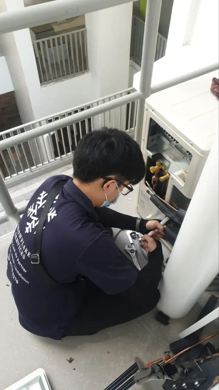 Technician performing a follow-up outdoor unit inspection with close checks on line and valve areas.